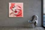 Female face emerging through coral pink geometric paper layers, bold red lips portrait mixed-media canvas for living room