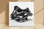 Glossy black abstract sculpture with looping voids on white background, bold minimalist wall art canvas for living room