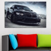 Zwarte BMW sportcoupé recht van voren gefotografeerd op een dak onder onweerswolken, canvasprint met auto