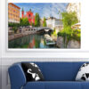 A Venice canal scene with gondolas moored along historic buildings under a soft blue sky