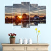 Five connected panels show a city skyline at sunset, silhouetted against warm orange and pink skies