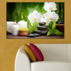 White orchid blooms rest alongside smooth black stones on dark water