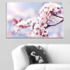 Pink and white blossoms cluster along a natural tree branch against a soft neutral background