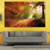 A tree-lined path winds through autumn forest, framed by warm orange and golden foliage overhead