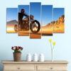 A motorcyclist crosses Death Valley terrain under daylight, captured across five connected panels