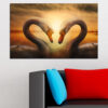 Two swans glide across calm water beneath a sunset sky filled with warm orange, pink, and soft purple tones