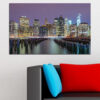 Denna canvas visar Brooklyn skyline silhuetterad mot varmt solnedgångsljus, med reflektioner som sträcker sig över vattnet