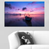 A sailboat glides across calm water beneath a warm sunset