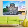 A medieval stone castle stands beside calm river waters, its towers and walls mirrored in the still surface
