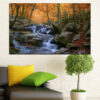 A waterfall flows through an autumn forest, framed by golden leaves and moss-covered rocks