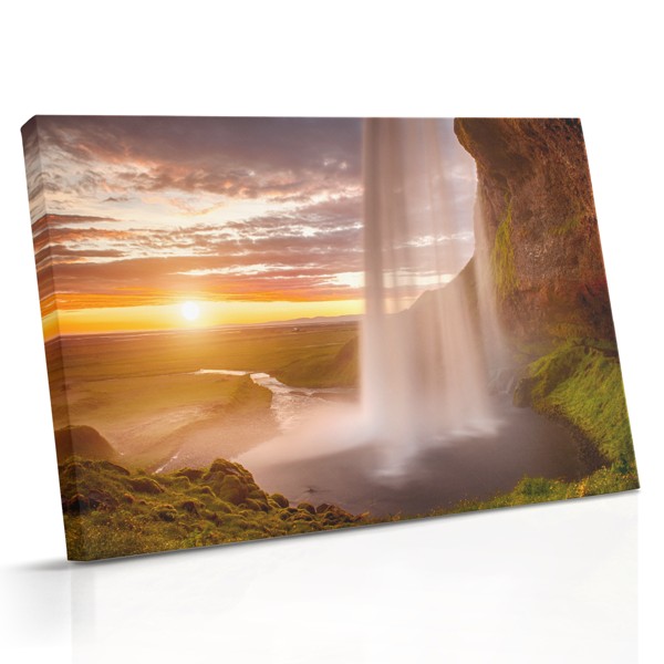 Uma cascata desce sobre rochas sob um céu quente ao pôr do sol